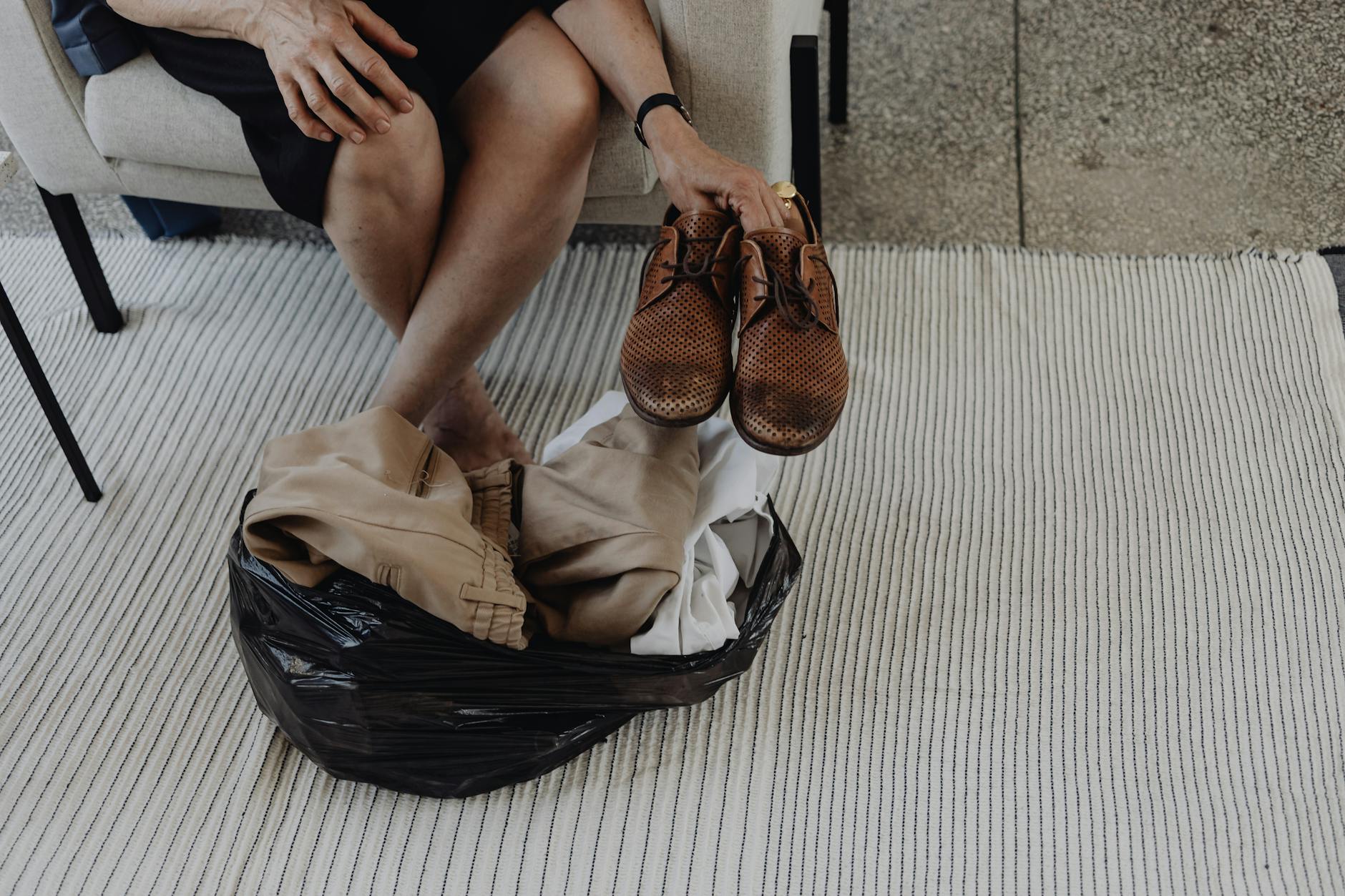 Osoba na dywanie porządkuje ubrania i buty wyjęte z torby