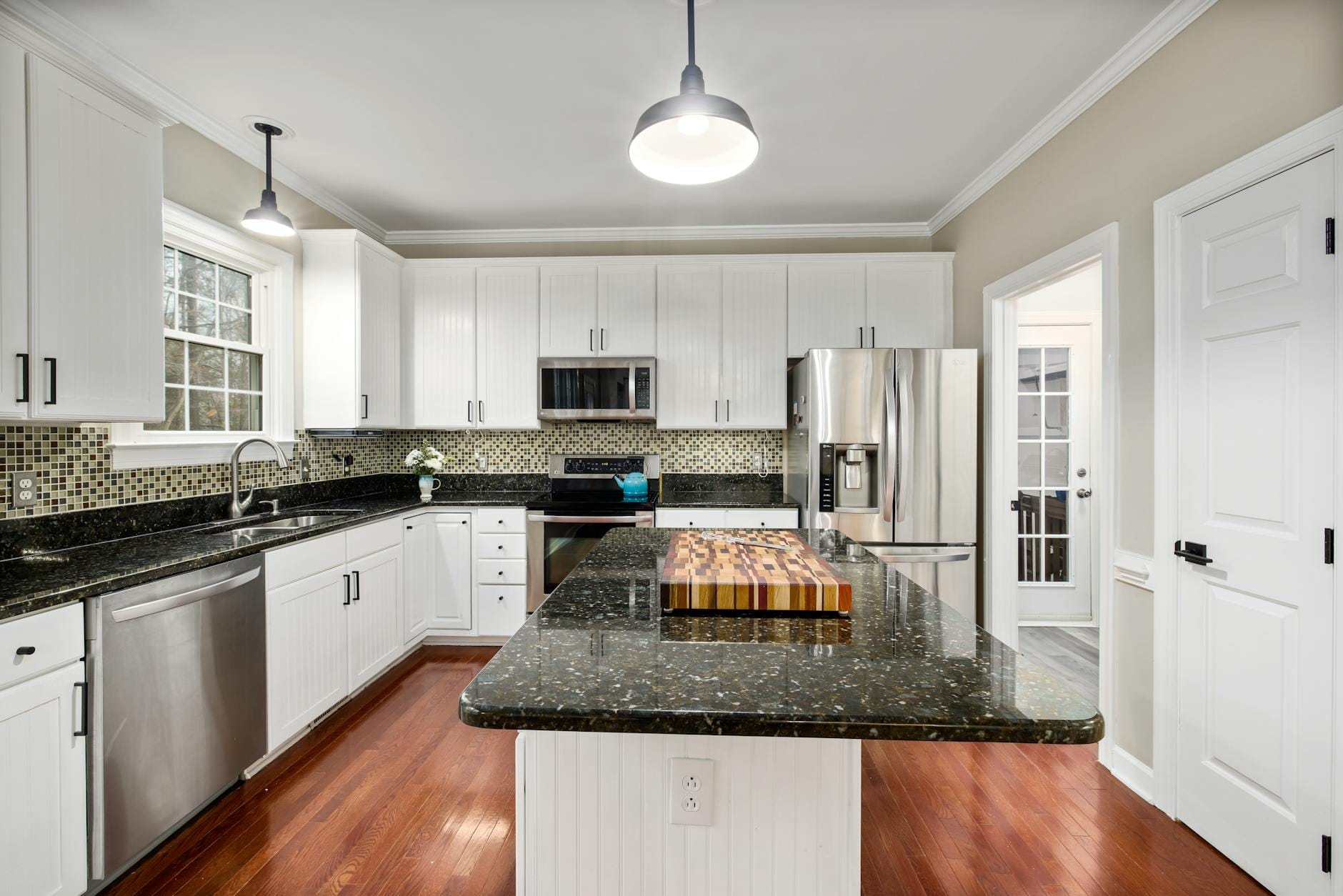 Nowoczesna biała kuchnia z czarnym blatem i stalowym AGD