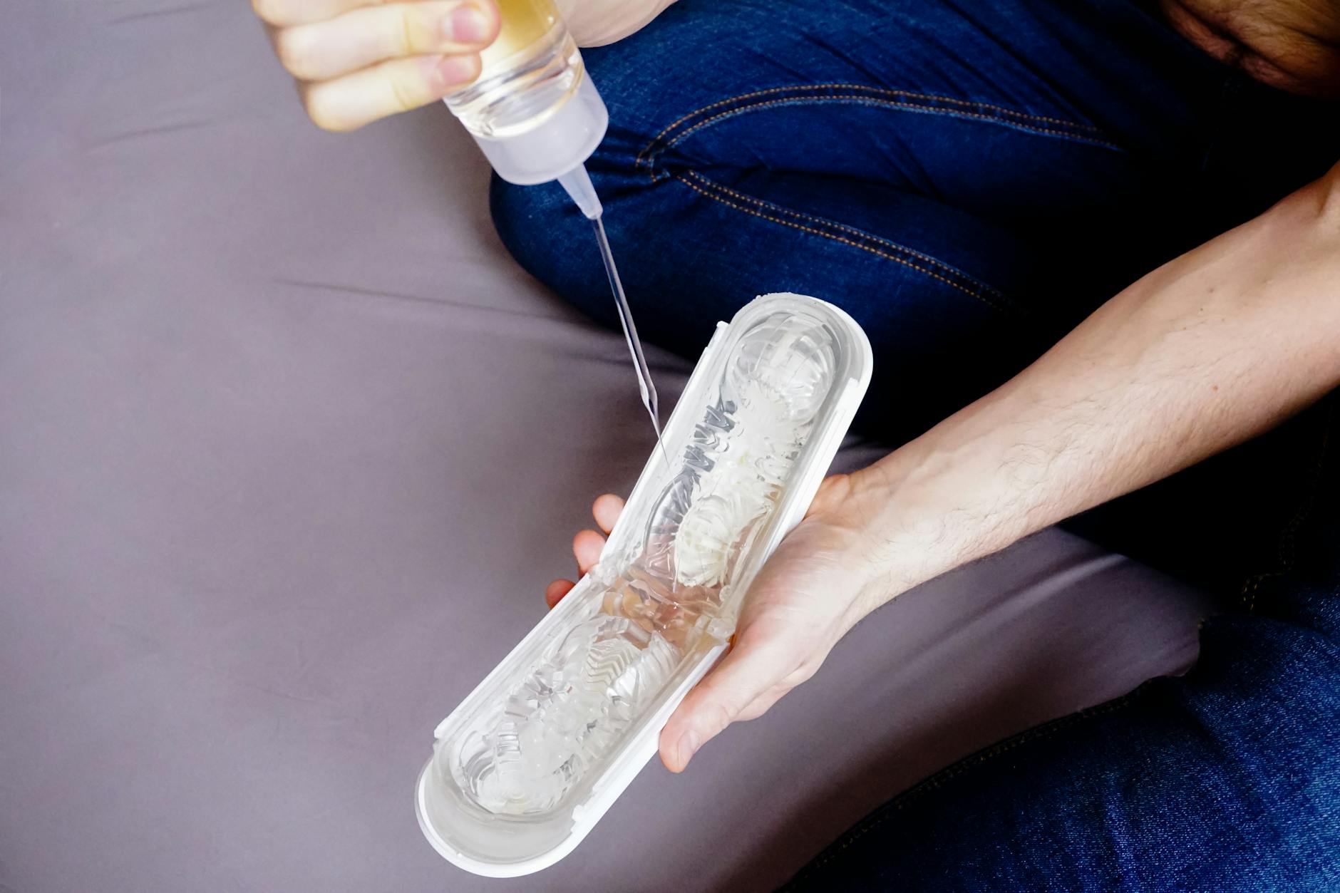 Dłonie nakładające lubrykant na erotyczny gadżet