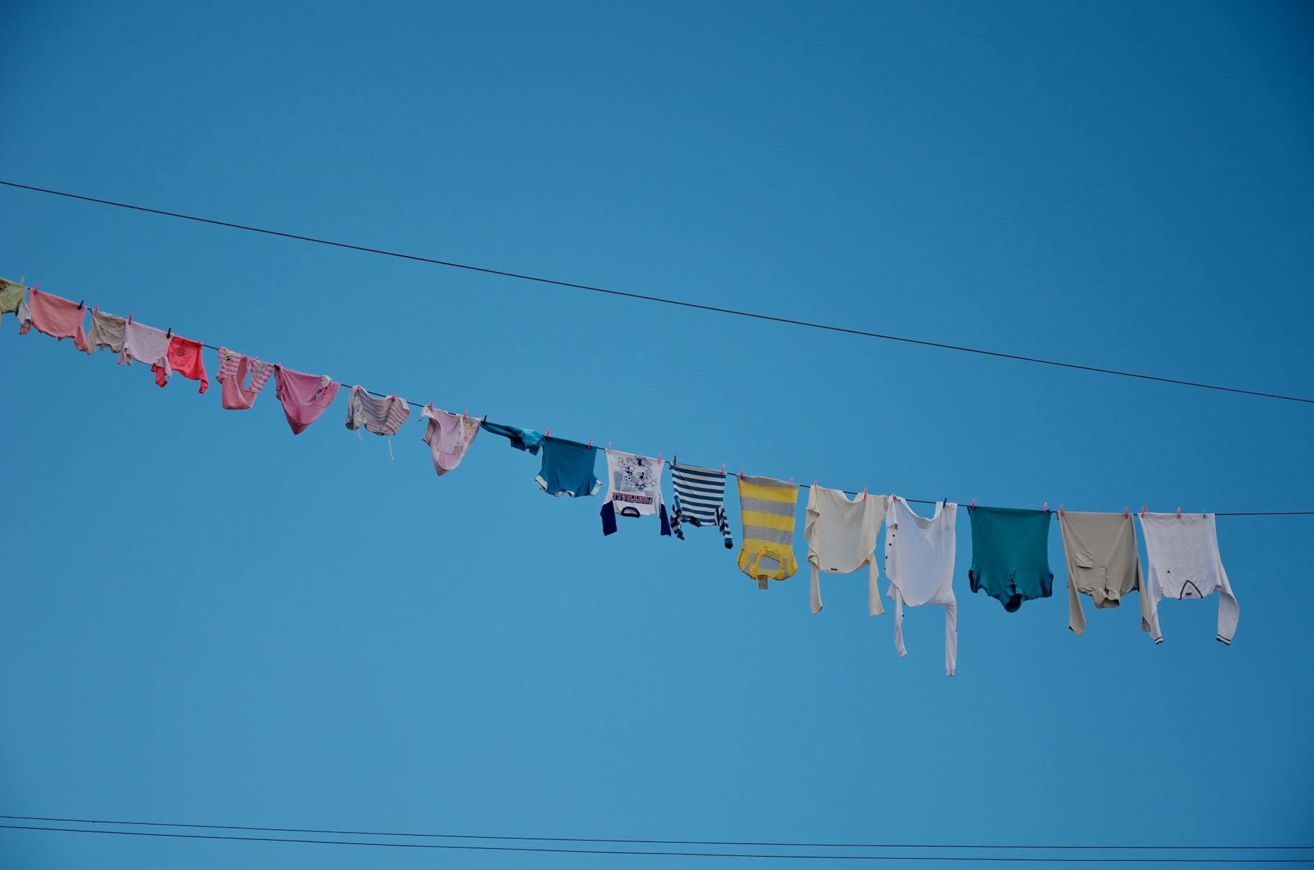 Kolorowe pranie na sznurze suszy się na słońcu na tle błękitnego nieba