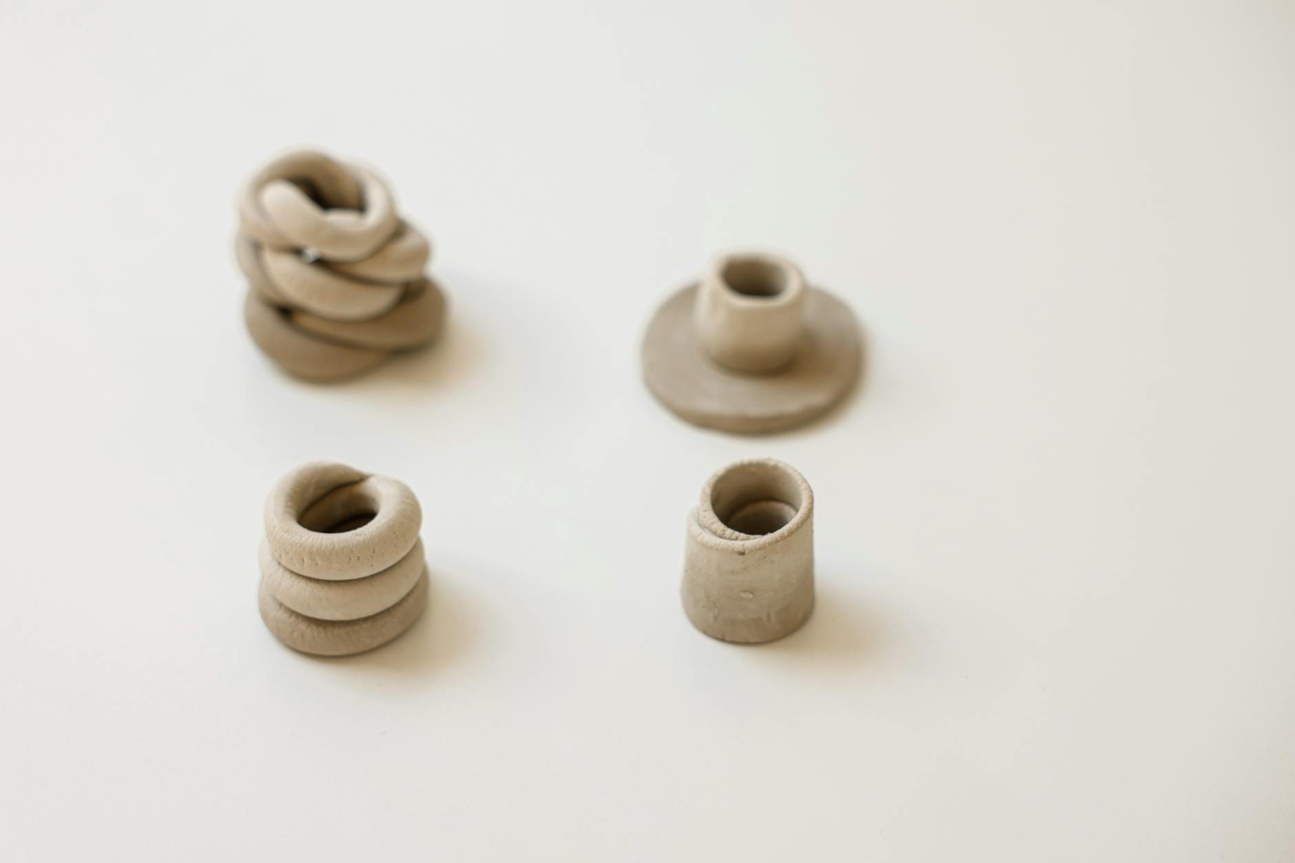 Dekoracje DIY z gliny samoutwardzalnej do domu w stylu hygge krok po kroku Cztery minimalistyczne rzeźby z gliny samoutwardzalnej na białym tle