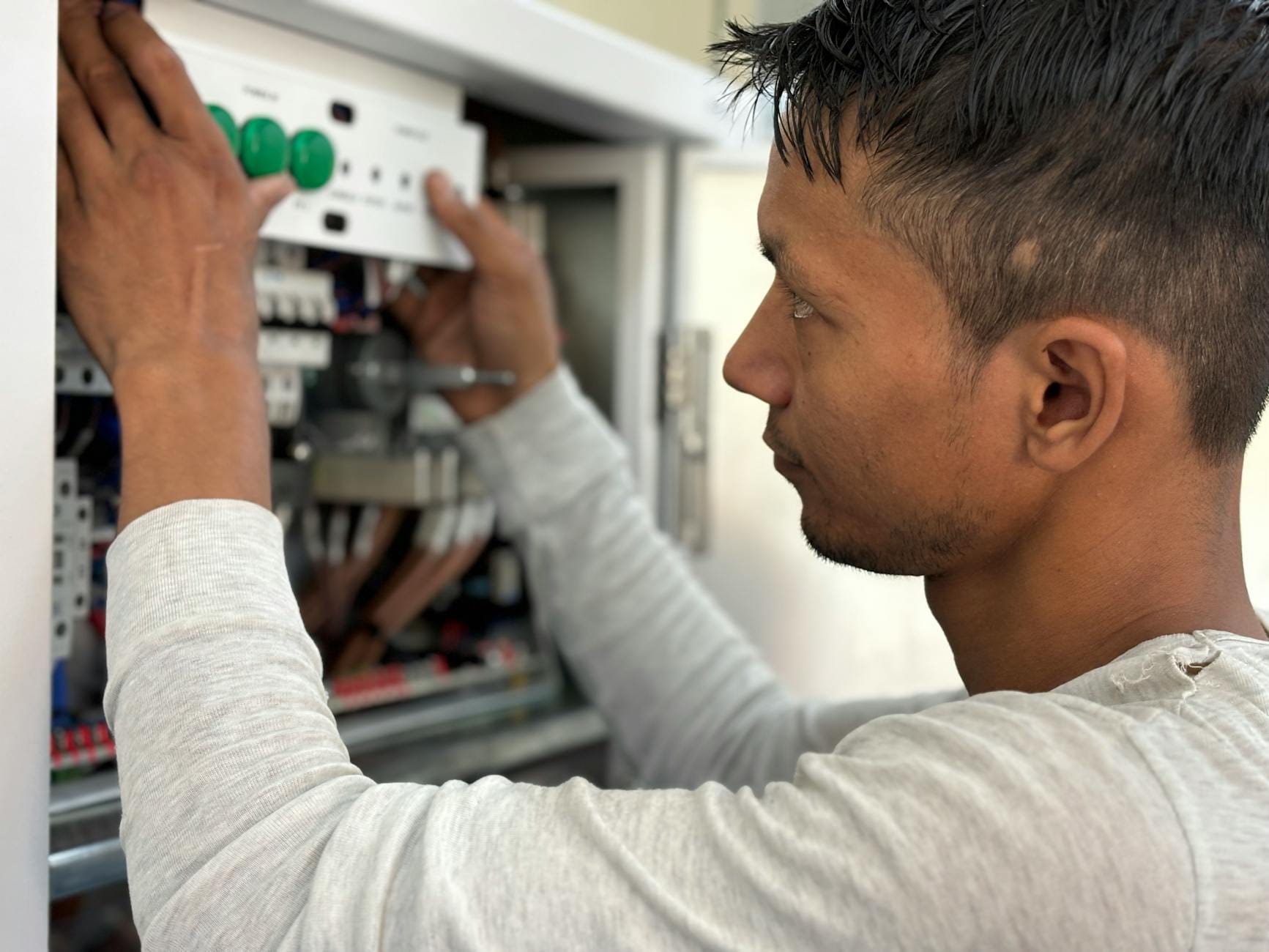 Elektryk w skupieniu reguluje wyłączniki w rozdzielnicy elektrycznej