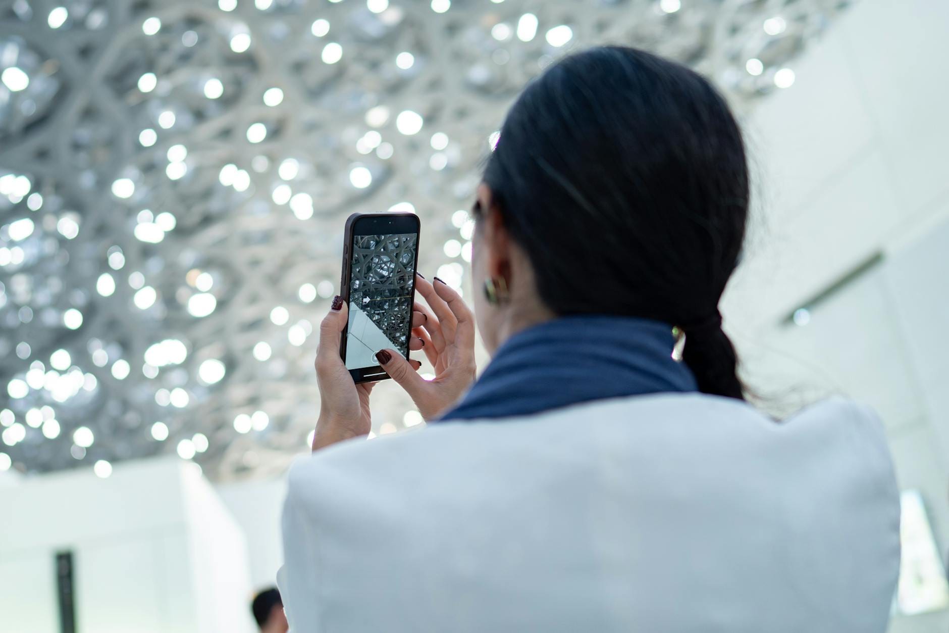 Kobieta fotografuje ozdobny sufit smartfonem w mieszkaniu