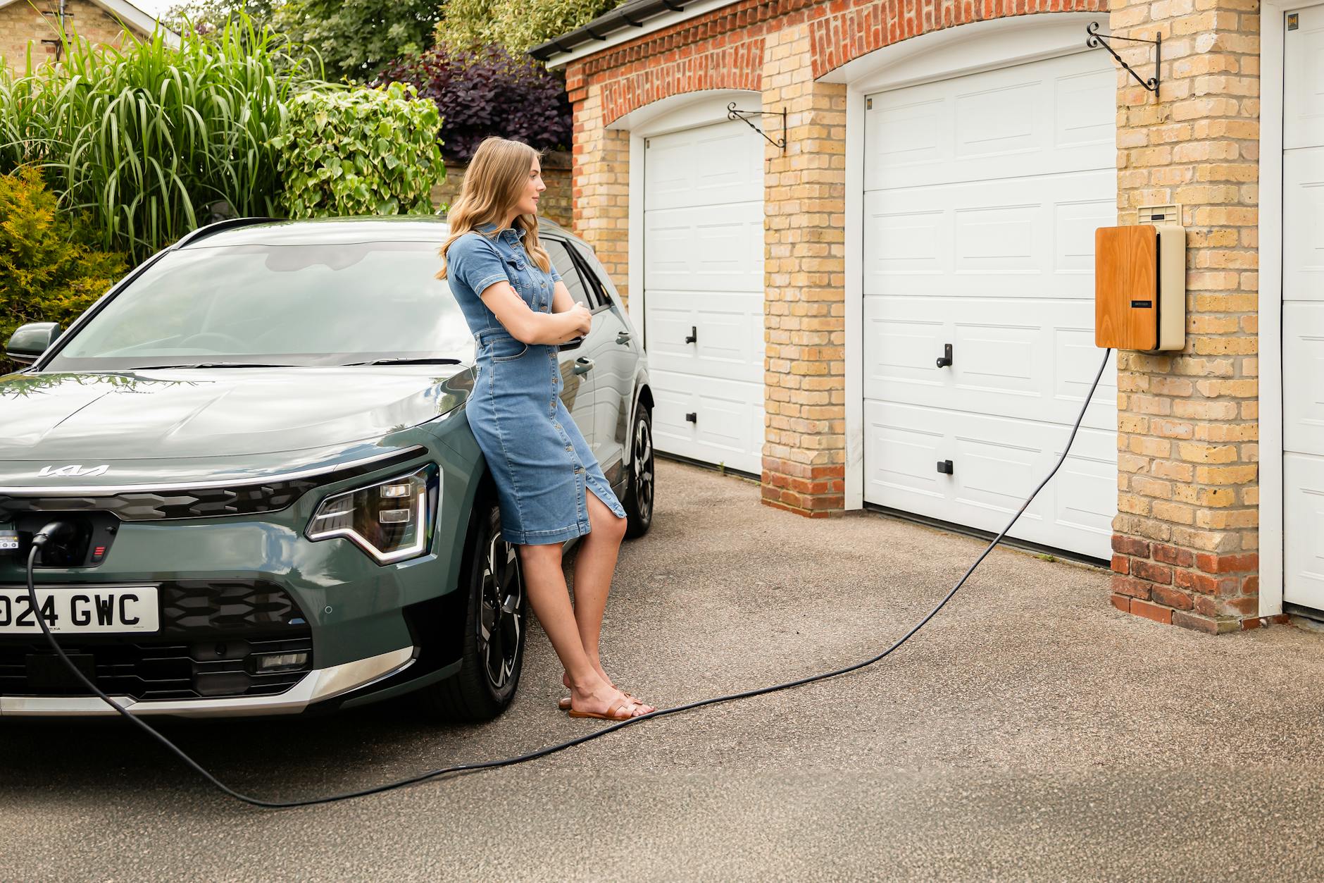 Kobieta podłącza auto elektryczne do domowej stacji ładowania