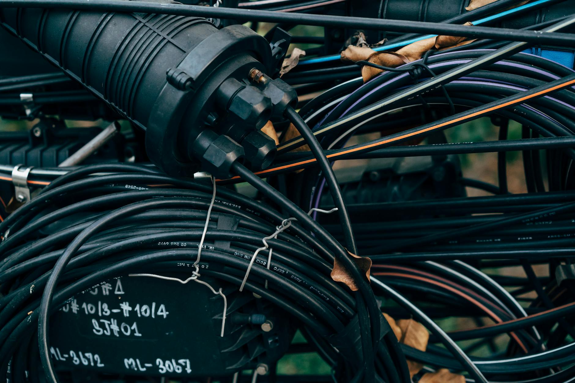 Plątanina czarnych kabli i złączy w zewnętrznej instalacji telekomunikacyjnej
