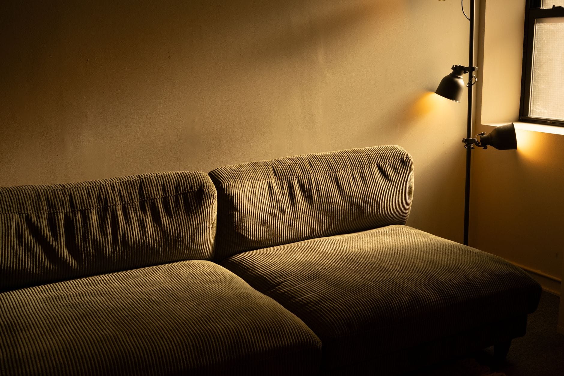 Tanie triki na ciepło: zasłony, dywany i folie, które pomagają zimą Sztruksowa sofa w przytulnym, słabo oświetlonym salonie zimą