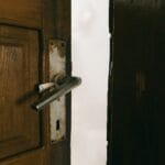 Jak wyregulować drzwi wewnętrzne, które ocierają o podłogę Lekko uchylone rustykalne drewniane drzwi z metalową klamką